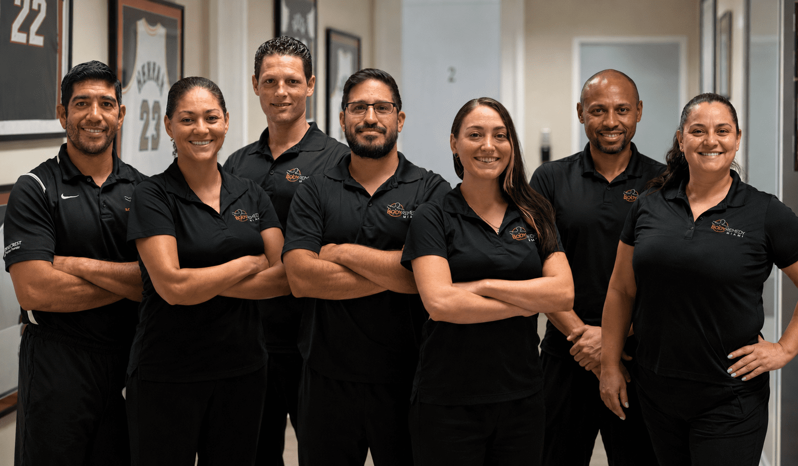 Seven smiling staff in black polo shirts
